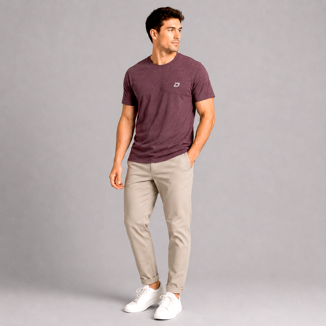 Male model wearing the maroon D Mark Tri-Blend Tee featuring an embroidered D Mark logo, paired with light khaki pants and white sneakers in a clean studio setting that highlights the shirt’s premium comfort and versatile everyday style.