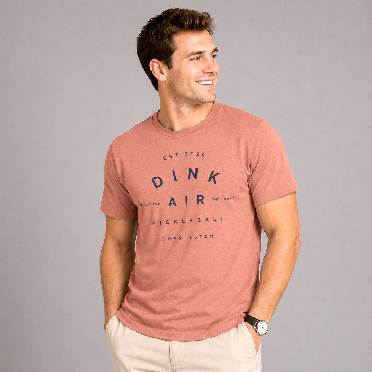 Male model wearing the mauve Charleston Club Tee with a vintage-inspired Dink Air graphic, styled with neutral shorts in a premium lifestyle setting.