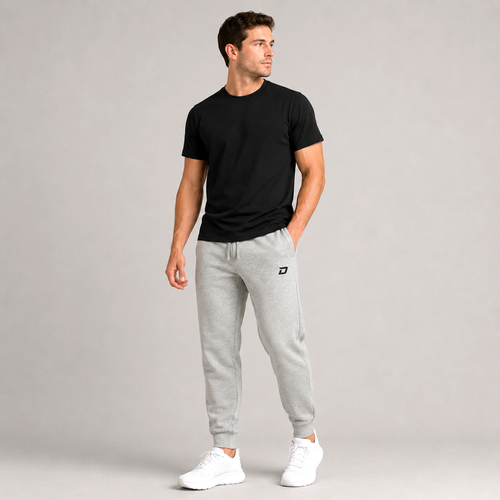 Male model wearing the Dink Air Classic Joggers in gray featuring an embroidered black D Mark logo, tapered athletic fit, lightweight performance fabric, elastic waistband, ribbed ankle cuffs, and a clean minimalist design for pickleball, training, travel, recovery, and everyday wear.