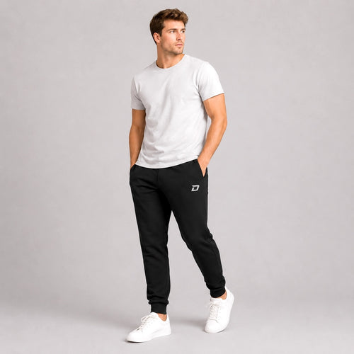 Male model wearing the Dink Air black Classic Joggers with a white tee in a casual lifestyle setting.