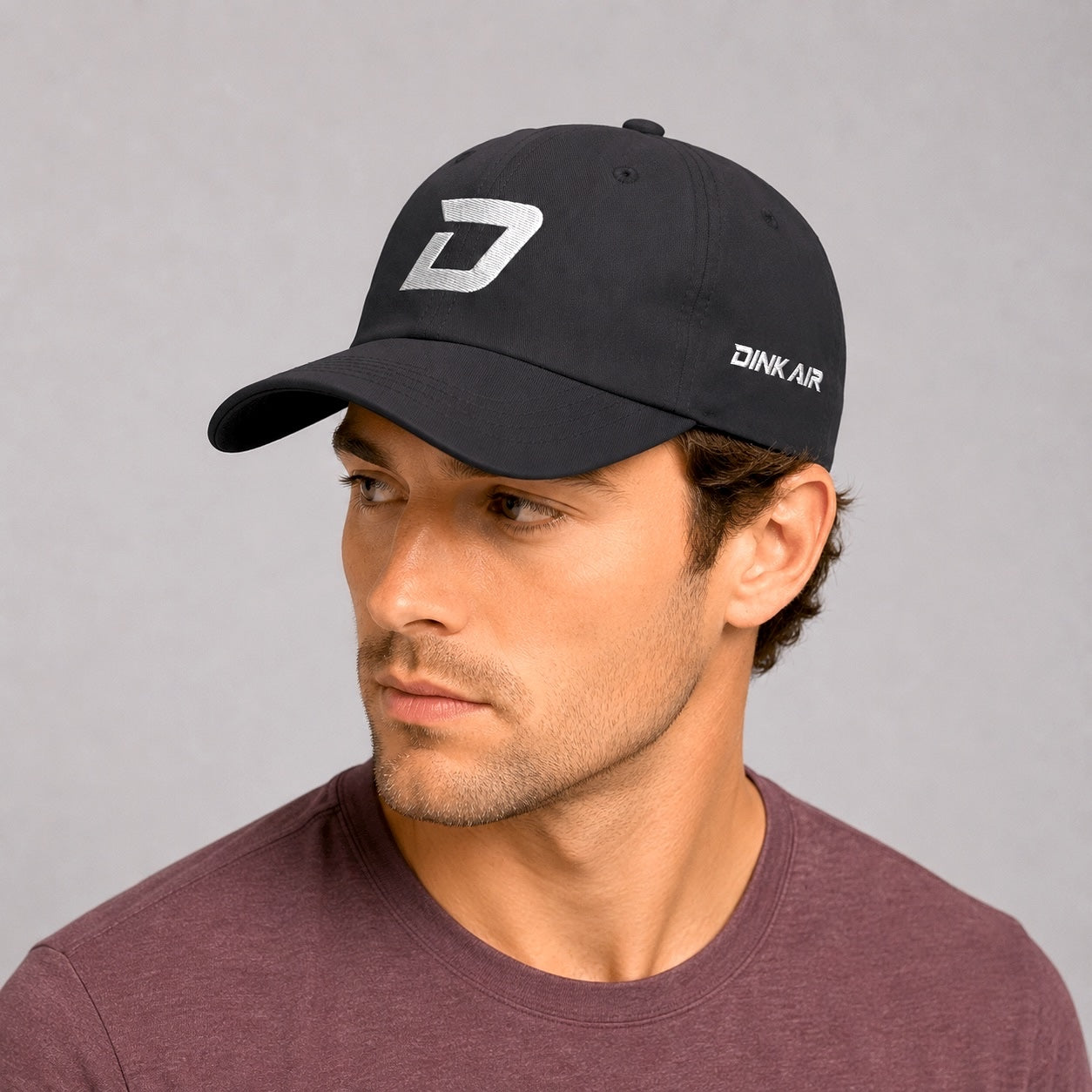 Lifestyle image of a male model wearing the charcoal D Mark Classic Cap with a casual athletic outfit.