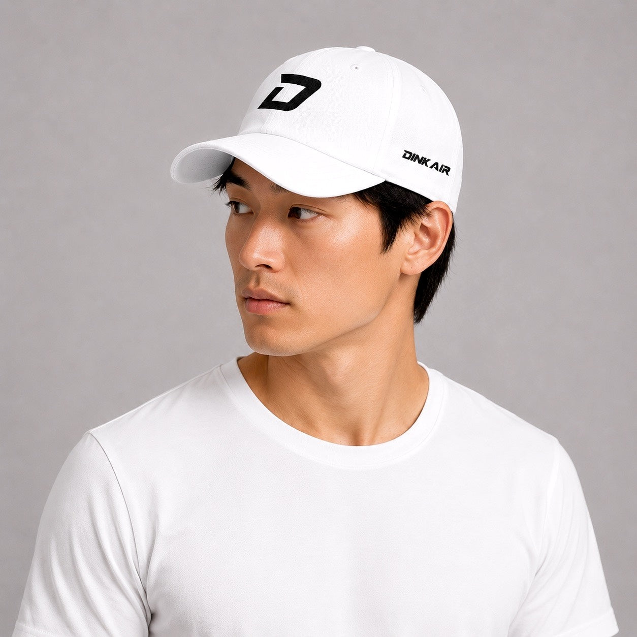 Lifestyle image of a male model wearing the D Mark Classic Cap in white with a casual athletic outfit.