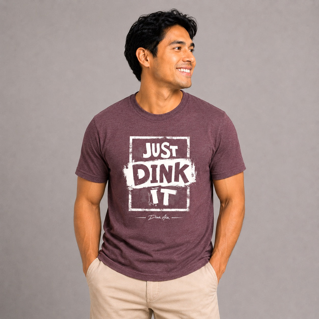 Male model wearing the Just Dink It Premium Tri-Blend Tee in maroon with a distressed white "Just Dink It" graphic, paired with khaki pants in a clean studio setting, showcasing the ultra-soft premium tri-blend fabric and relaxed athletic fit.