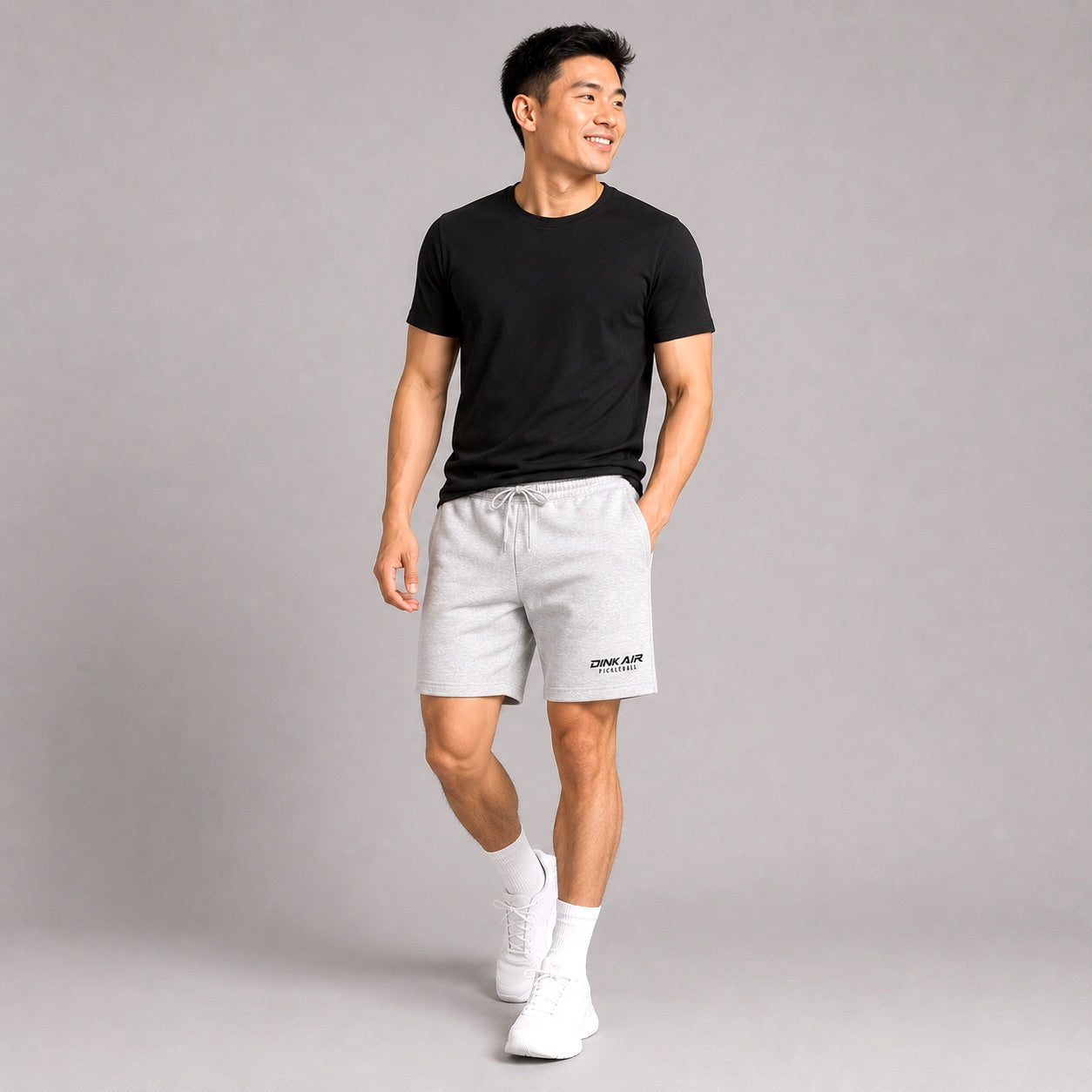 Male model wearing the gray Signature Pickleball Fleece Shorts and a black Dink Air tee in a casual lifestyle setting.