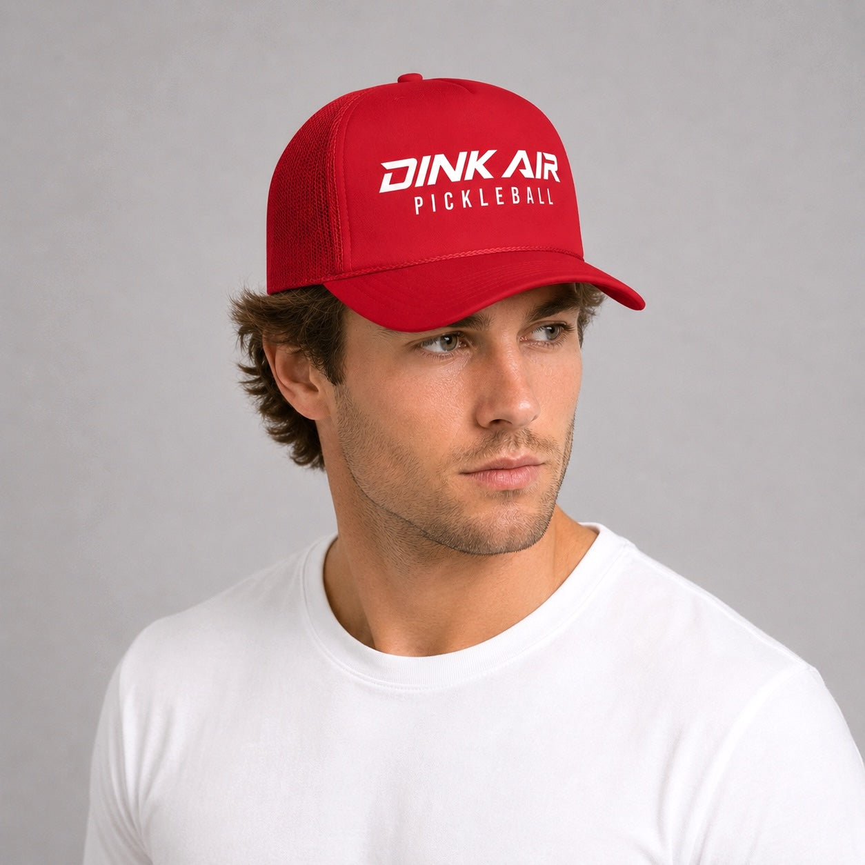 Male model wearing the red Signature Pickleball Trucker Hat in a casual athletic setting.